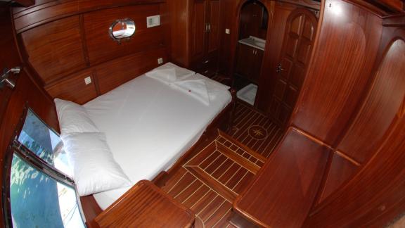 A comfortable cabin on the Gulet Sahinoğlu with a large double bed, wood panelling and an adjoining bathroom.